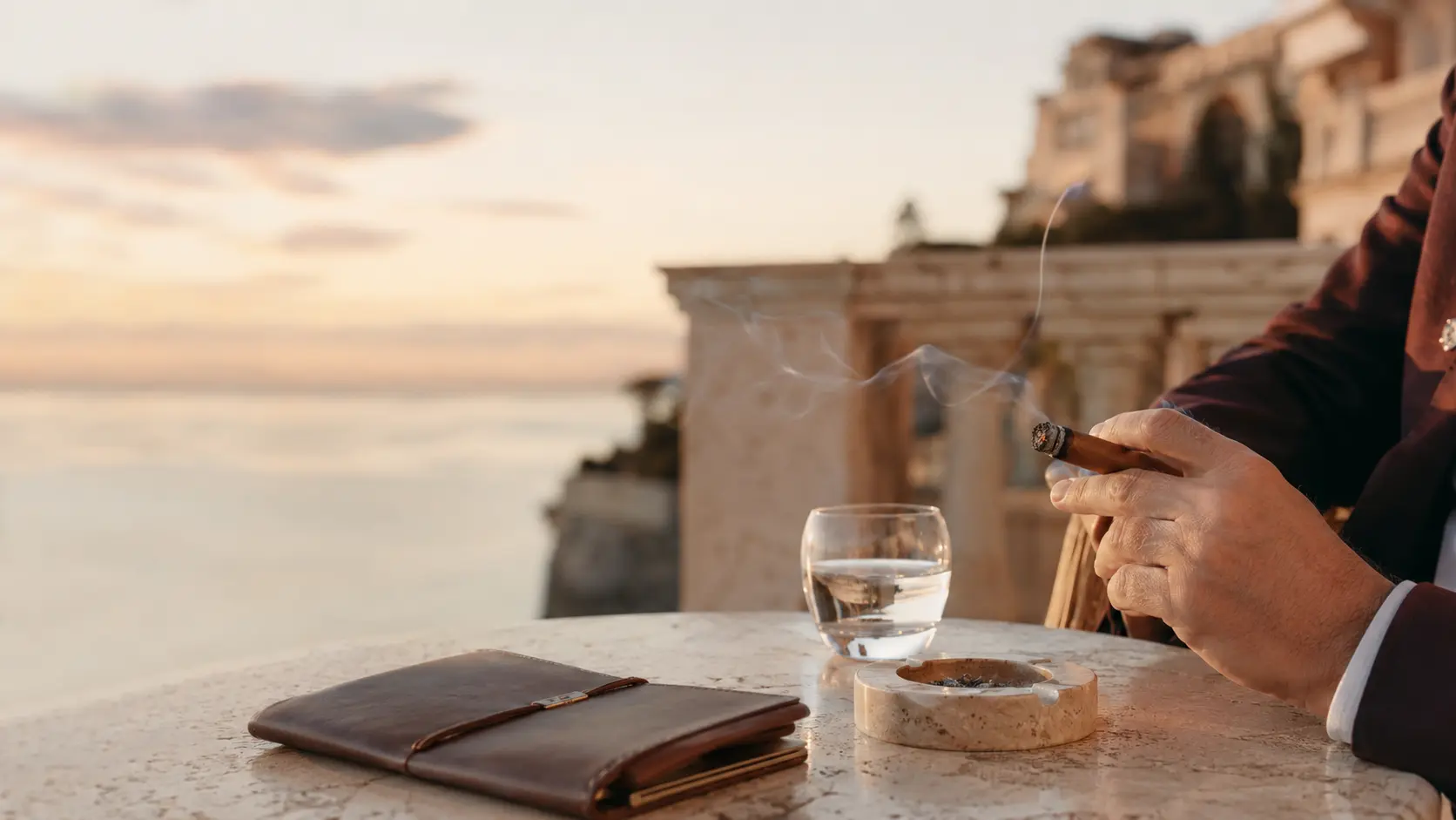 A cigar enthusiast holding a Monte-Carlo Club® cigar on a terrace overlooking the Mediterranean.